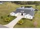 Aerial view of white home with brick driveway, complemented by a pond, lush lawn, and mature trees at 3409 Lake Diane Rd, Tavares, FL 32778