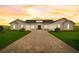 Stunning white modern farmhouse featuring a brick drive, manicured lawn, and sunset skies at 3409 Lake Diane Rd, Tavares, FL 32778