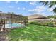 Fenced backyard featuring green grass, screen-enclosed pool, and well-manicured landscaping at 3637 Rothbury Dr, Belle Isle, FL 32812