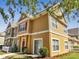 Charming townhouse with red door, light yellow siding, sidewalk, and well-manicured front lawn at 4561 Yellowgold E Rd # 107, Kissimmee, FL 34746