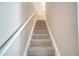 Carpeted staircase featuring a white handrail and neutral-colored walls at 4561 Yellowgold E Rd # 107, Kissimmee, FL 34746