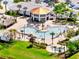 Aerial view of community pool, pool-side seating, covered bar area, mature trees and landscaping, and water views at 4672 Tribute Trl, Kissimmee, FL 34746