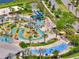 Aerial view of community lazy river, splash pad, slide, pool-side seating, and lush landscaping at 4672 Tribute Trl, Kissimmee, FL 34746