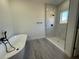 Modern bathroom featuring marble-tiled shower and soaker tub with wood-look flooring at 4863 Sw 159Th Ln Rd, Ocala, FL 34473