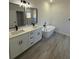Bathroom featuring double vanity, bathtub and walk-in shower with wood-look flooring at 4863 Sw 159Th Ln Rd, Ocala, FL 34473