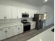 Modern kitchen with stainless steel appliances, white cabinets, quartz countertops, and modern tile backsplash at 4863 Sw 159Th Ln Rd, Ocala, FL 34473