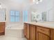Bright bathroom with tile flooring, a garden tub, and wooden vanity at 501 Heartwell Dr, Poinciana, FL 34759