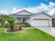 Charming single-story home featuring well-manicured lawn, landscaped yard, and a 2-car garage at 501 Heartwell Dr, Poinciana, FL 34759