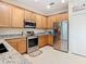 Modern kitchen with stainless steel appliances, granite countertops, and light wood cabinets at 501 Heartwell Dr, Poinciana, FL 34759