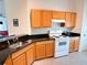Well-lit kitchen with oak cabinets, black countertops, and modern appliances at 585 Grand Canal Dr, Poinciana, FL 34759