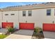A home featuring white walls and red garage doors at 7063 Nemours Pkwy, Orlando, FL 32827