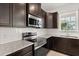 A modern kitchen with stainless steel appliances, dark wood cabinets, and a granite countertop at 7063 Nemours Pkwy, Orlando, FL 32827