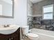 Stylish bathroom features a vanity, toilet, and tub with unique gray tile surround and a window at 11125 Finchley Pl, Orlando, FL 32837