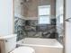 Bathroom showcasing marble-like tiling with accent border, tub, and updated fixtures at 11125 Finchley Pl, Orlando, FL 32837