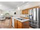 Large kitchen with island sink and seating area, open to living area with stainless refrigerator at 1129 Dartford Dr, Kissimmee, FL 34758