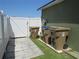 This exterior view shows trash and recycle bins alongside a white vinyl fence and the home's green exterior wall at 1155 Roan Ct, Kissimmee, FL 34759