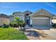 Charming home with a manicured lawn, decorative shrubs, and an attached two-car garage at 121 Fitzgerald Ln, Davenport, FL 33837