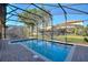 Sparkling pool enclosed by a screen, surrounded by lush greenery and brick pavers, perfect for outdoor relaxation and enjoyment at 1454 Myrtlewood St, Davenport, FL 33896