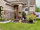 Close-up of a home's front entrance with brick accents, a landscaped garden and verdant grass at 14945 Huntcliff Park Way, Orlando, FL 32824