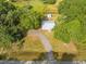 Aerial view showcasing a property with home, outbuilding, a gravel driveway, and mature landscaping at 150 N Post Office Rd, Kenansville, FL 34739