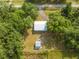 Aerial view of property with house, outbuilding, driveway, and surrounded by lush green trees at 150 N Post Office Rd, Kenansville, FL 34739