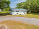 Charming single-story home with a gravel driveway, mature trees, and fresh exterior paint at 150 N Post Office Rd, Kenansville, FL 34739