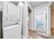 Hallway laundry area has stackable washer/dryer next to bathroom with blue shower curtain at 150 N Post Office Rd, Kenansville, FL 34739