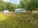 Expansive property featuring a light blue house, outbuilding, and surrounded by mature trees at 150 N Post Office Rd, Kenansville, FL 34739