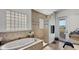 Bathroom featuring a large soaking tub, a glass block window and a walk out to balcony at 1506 Euston Dr, Reunion, FL 34747