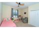 Well-lit bedroom with ceiling fan, colorful decor, and comfortable seating area at 1599 Thetford Cir, Orlando, FL 32824
