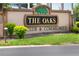 Community entrance sign for The Oaks Club & Community with green landscaping at 1607 Tail Feather Dr, Kissimmee, FL 34746