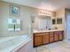 Bathroom featuring double sinks, tile flooring, large mirror, and bathtub with jets at 1915 Acacia Dr, Kissimmee, FL 34758