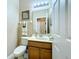 Well-lit powder room features a vanity with wood cabinets, a toilet and decorative art at 1915 Acacia Dr, Kissimmee, FL 34758
