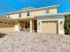 Charming two-story home featuring a welcoming front porch and a three-car garage with brick paver driveway at 1915 Acacia Dr, Kissimmee, FL 34758
