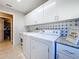 Well-lit laundry room showcasing white cabinets, granite counters, washer, dryer, and tile backsplash at 1915 Acacia Dr, Kissimmee, FL 34758
