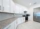 Contemporary kitchen boasts white cabinets, granite countertops, stainless appliances, and tile flooring at 219 Summerlin Loop, Haines City, FL 33844