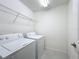 Functional laundry room featuring a washer, dryer, and overhead shelving for storage at 219 Summerlin Loop, Haines City, FL 33844