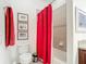 Bathroom with red shower curtain, toilet, and framed art prints on the wall at 2502 Palm Tree Dr, Poinciana, FL 34759
