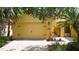 Attached two-car garage on yellow home featuring brick-paver driveway and manicured landscaping at 2502 Palm Tree Dr, Poinciana, FL 34759