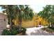 Attached two-car garage and manicured landscaping on yellow home featuring brick-paver driveway at 2502 Palm Tree Dr, Poinciana, FL 34759