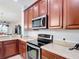Kitchen showcasing stainless steel appliances, wooden cabinets, stone countertops, and an attached microwave oven at 2502 Palm Tree Dr, Poinciana, FL 34759