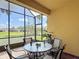 This outdoor screened in lanai features a table and chairs with a view of the neighborhood pond and landscaping at 2502 Palm Tree Dr, Poinciana, FL 34759