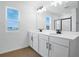Modern bathroom with double sinks, white cabinets, large mirror, and a window with view at 2943 Gavin Sky Dr, Kissimmee, FL 34744