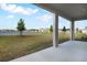 Covered back porch overlooking a spacious backyard with lake views and blue skies at 2961 Gavin Sky Dr, Kissimmee, FL 34744