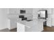 Modern white kitchen featuring an island with quartz countertops, stainless steel appliances, and wood-look tile flooring at 2967 Gavin Sky Dr, Kissimmee, FL 34744