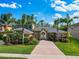 Inviting exterior showcasing manicured lawn, brick driveway, and mature landscaping with a colorful array of flowers at 3245 Heirloom Rose Pl, Oviedo, FL 32766