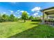 Expansive backyard featuring lush green grass, mature trees and a covered patio with decorative outdoor furniture at 3447 Feathergrass Ct, Harmony, FL 34773