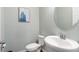 Stylish half bathroom featuring a pedestal sink, toilet, and tasteful artwork on the light-blue wall at 3447 Feathergrass Ct, Harmony, FL 34773