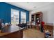 Office with two large windows, dark blue accent wall and hardwood floors at 3447 Feathergrass Ct, Harmony, FL 34773