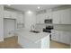 Bright, all-white kitchen featuring an island with sink and stainless steel appliances at 4075 Bannock Ave, Tavares, FL 32778